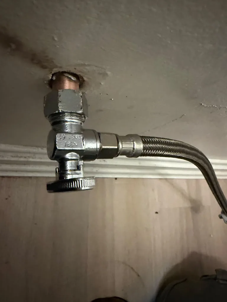 New angle stop shutoff valve installed on a supply line under a sink